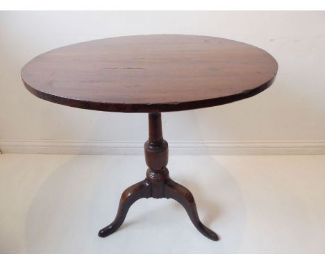 A George II period circular tilt-top oak occasional table, turned stem and tripod base (76cm diameter)
