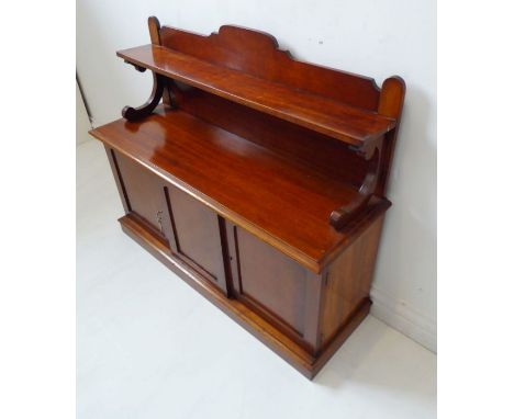 An usual miniature 19th century mahogany chiffonier; the shelved superstructure above a central panelled door sliding to reve