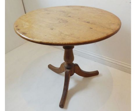 A 19th century circular tilt-top pine occasional table; turned stem and on tripod base with downswept legs (72cm diameter)