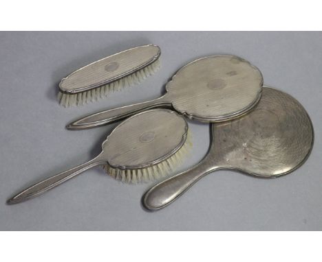 An engine-turned silver mounted hand mirror, hair brush, &amp; clothes brush, Birmingham 1955 by Adie Bros.; &amp; a similar 