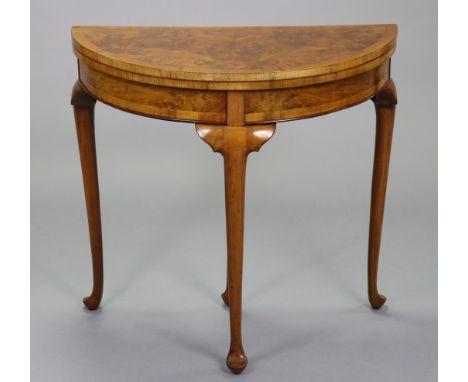 An early/mid-20th century burr walnut veneered card table with demi-lune fold-over top inset green baize, on four turned &amp
