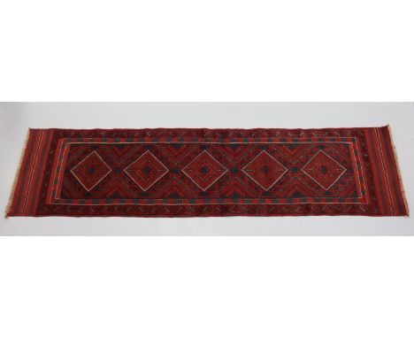 A Meshwari runner of madder ground, with central row of five lozenges in chequered &amp; hook borders; 8’4” x 2’1”.