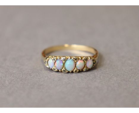 An opal ring, the five graduated oval stones set within a border of diamond chips to an un-marked yellow metal shank; size: R