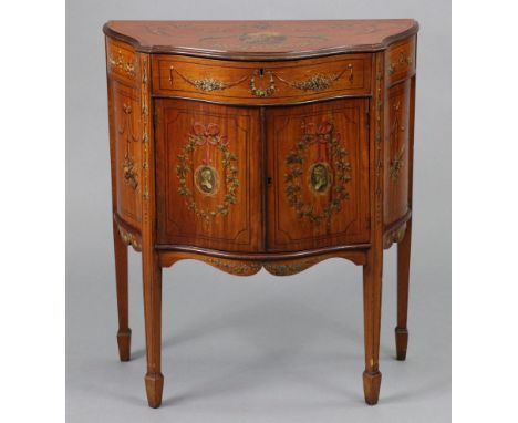 An Edwardian Sheraton revival mahogany small serpentine-front cabinet, with all-over painted decoration, the hinged lift-lid 