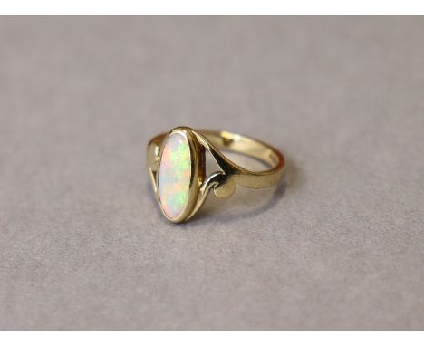 A 9ct. gold ring set elongated oval opal between open scroll shoulders; size: L; weight: 2.5 gm.