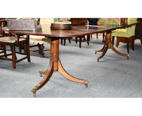 A 19th century mahogany twin pillar dining table with two additional leaves, with brass paw feet and moving on castors, 295cm