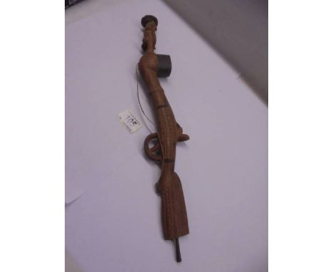 A Black Forest? carved novelty pipe of a figure standing on a rifle, 45 cm long.