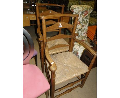 Pair of stylised Arts & Crafts design oak ladder back elbow chairs with rush seats, turned legs.