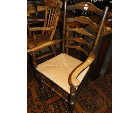 An oak ladder back and rush seated elbow chair on pad foot.