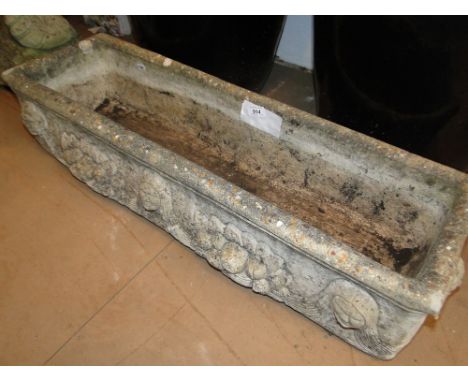 A weathered concrete rectangular garden planter.