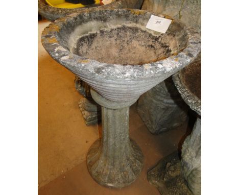 A weathered concrete garden planter on pedestal.