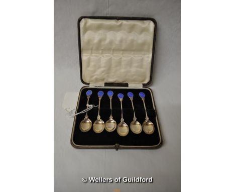 A set of six white metal coffee spoons with blue enamel terminals, stamped 'silver', cased.