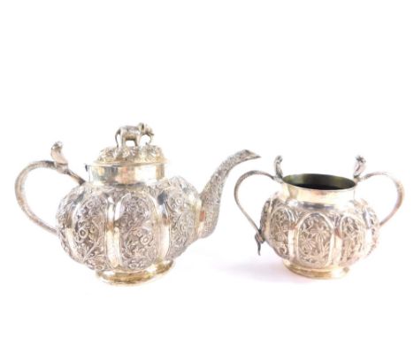 A 19thC Indian part tea set, white metal, the teapot with cobra handle, of fluted globular form, embossed with panels of flow