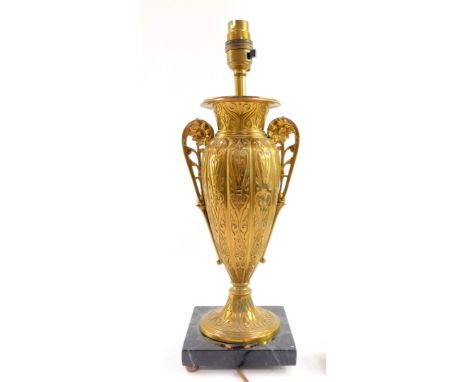 A late 19th continental brass table lamp, of twin handled vase form, engraved with foliate scrolls, raised on a square marble