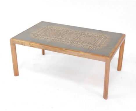 A 1960's pottery tile topped coffee table, with teak frame of rectangular form, on canted legs, the top set with sun motif se