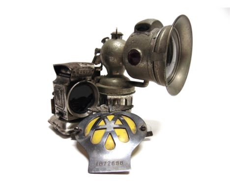A MILLER 'REGALITE' MODEL MOTORCYCLE CARBIDE LAMP  17cm high; A Lucas 'Warna' bicycle oil lamp, 10cm high; AA badge (IB72688)
