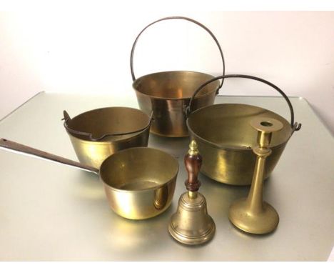 A brass bell, a brass candlestick, a brass saucepan with cast iron handle, three various brass preserve pans two with folding