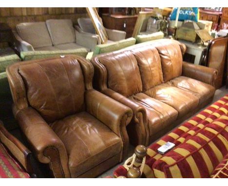 A modern two piece lounge suite comprising a three seater sofa and easy chair in brown hide with studded detail (sofa no legs