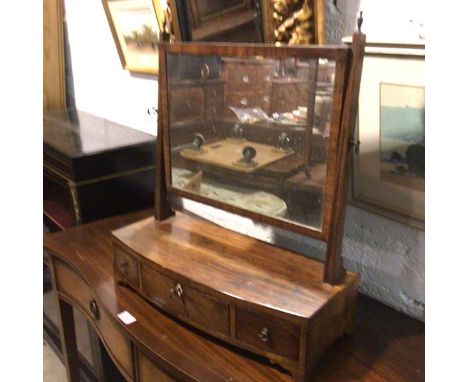 A 19thc mahogany bow front swing mirror raised on square tapered supports with brass urn finials, fitted three drawers, raise