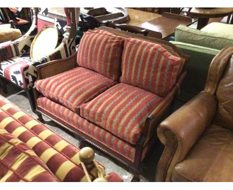 A mahogany framed two seater bergere sofa with double caned panel sides and back, upholstered with loose cushions in red and 