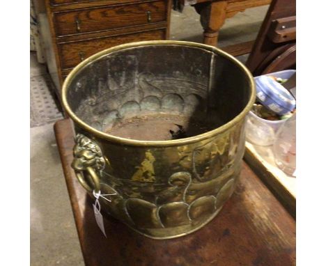 An Edwardian embossed brass circular coal bucket with Viking longboat style chased panel with lion mask ring handles to side,