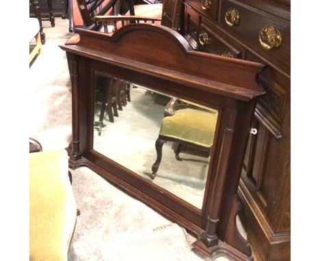 An Edwardian walnut overmantel with arched top above a rectangular frame bevelled glass wall mirror, flanked by ring turned c