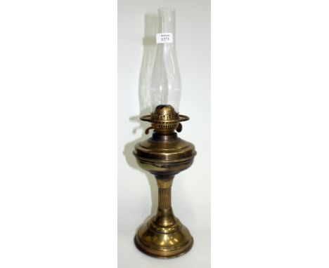 AN OLD BRASS OIL LAMP with reeded column support on circular spreading base, 58cm high overall