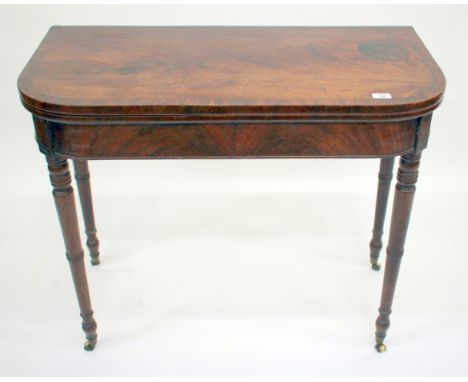 A GEORGIAN MAHOGANY FOLD OVER CARD TABLE with rounded front corners, cross banded top and standing on ring turned tapering le