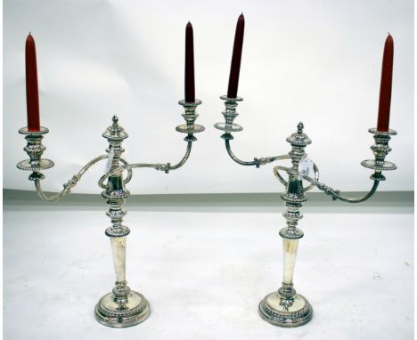 A PAIR OF SILVER PLATED TWO BRANCH CANDELABRA with gadrooned drip pans, reeded arms, central removable finial, all on a circu