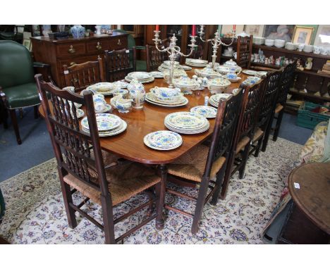 A REGENCY STYLE DINING TABLE standing on two tripod bases, 236cm long x 116.5cm wide including the extra leaf