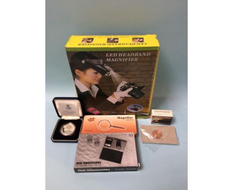 A silver coin, set of scales and magnifier etc.