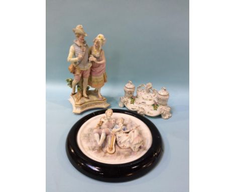 A Continental porcelain inkwell, a framed bisque circular plaque and a figure group (3)