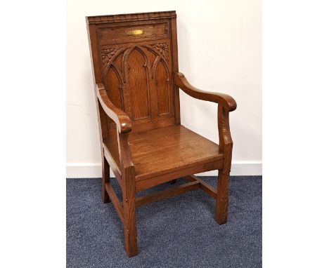 OAK GOTHIC CHAPEL ARMCHAIRthe carved panel back with a brass memorial plaque and shaped arms above a solid seat, standing on 