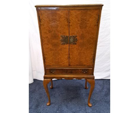 BURR WALNUT DRINKS CABINETwith a moulded top above canted corners flanking a pair of cupboard doors with an ornate Chinese st