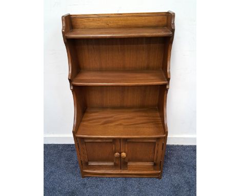 ERCOL ELM WATERFALL BOOKCASEwith two open shelves and shaped sides above a pair of panelled cupboard doors, standing on a pli