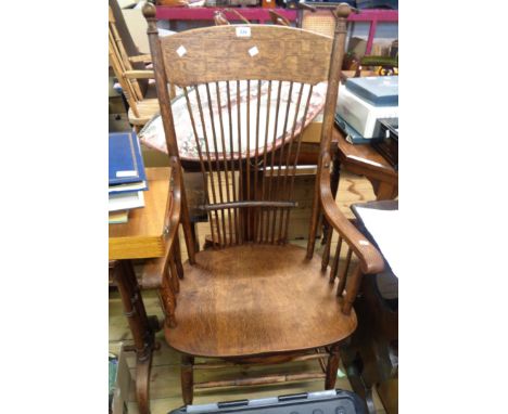 An early 20th Century oak framed high stick back elbow chair with swept armrests and moulded sectional solid seat, set on tur