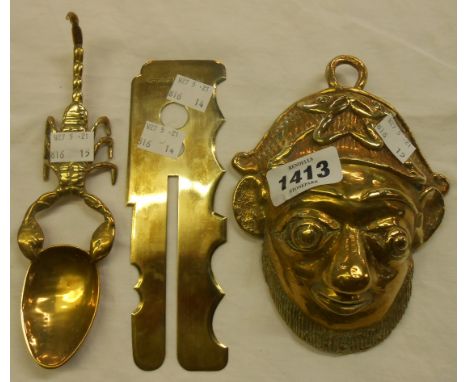 A brass scorpion pattern spoon, a military button stick, and a wall mask