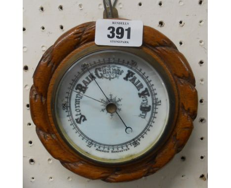 A 15.5cm diameter late Victorian oak framed aneroid wall barometer with rope twist border and printed ceramic dial