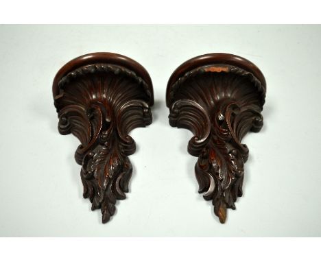 A PAIR OF CARVED MAHOGANY WALL SCONCES, with scroll and leaf moulded design under demi lune shelf, approximately 22cm high (a