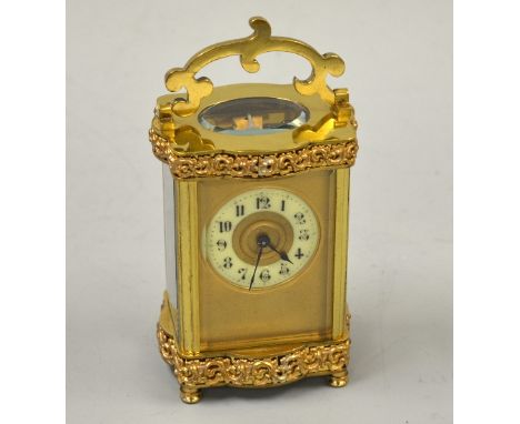 A BRASS CARRIAGE CLOCK, with pierced moulded borders to top and bottom rails, circular dial with Arabic numerals, slow/fast a