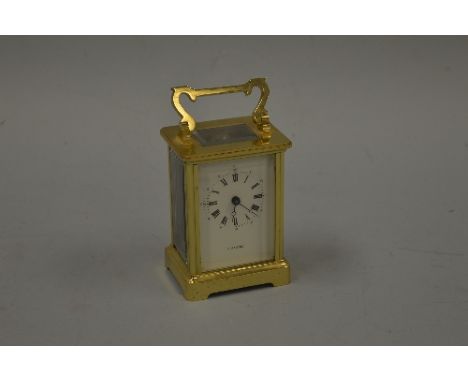 A BRASS CARRIAGE CLOCK, on shaped bracket plinth, with Roman numerals and H Samuel to face, approximately 8cm x 6cm x 11cm hi