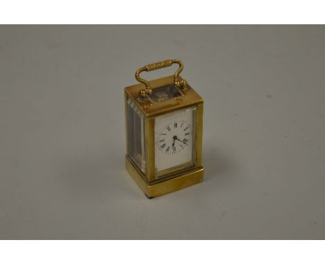 A SMALL BRASS CARRIAGE CLOCK, on plinth base with white enamelled dial with Roman numerals, movement stamped 'French Movement