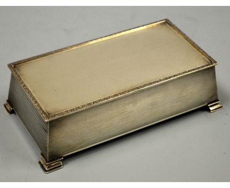 A SILVER ENGINE TURNED CIGARETTE BOX, of tapering rectangular form on stepped bracket feet, two division interior, Birmingham