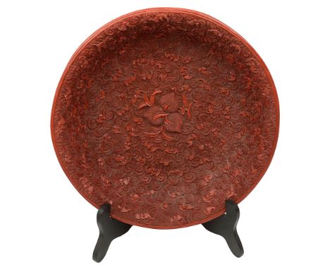 A Chinese cinnabar lacquer charger, 20th century, decorated to centre with three peaches, surrounded by repeating scroll moti