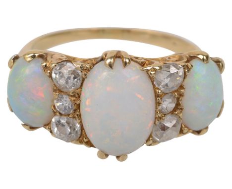 A late Victorian opal and diamond-set ring, the three cabochon opals separated by three old brilliant-cut diamonds, scrolling