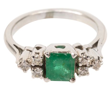 An emerald and diamond-set ringthe central step cut-cornered emerald set to either side with the three stone brilliant-cut di