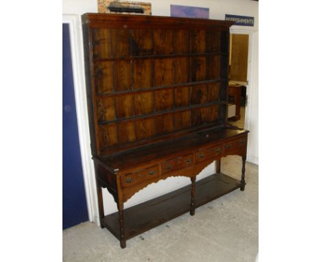 An 18th Century oak dresser with the three tier plate rack above a plain top, four short drawers each with brass swan neck ha