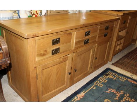 A light oak sideboard with three drawers above three cupboard doors