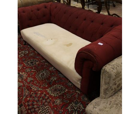 A Victorian Chesterfield button back sofa in red upholstery on turned and ringed front legs to brass caps and brown china cas