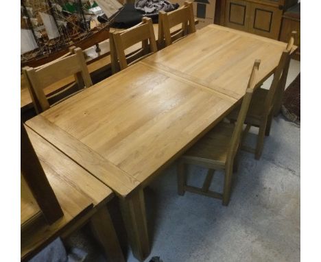 A light oak extending rectangular dining table on square section legs, together with six ladder back chairs